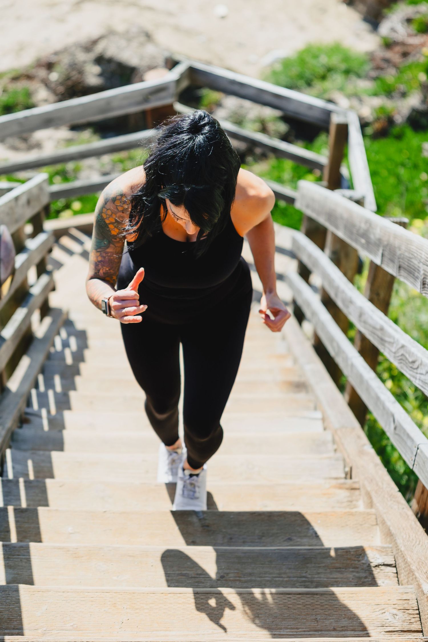 Person in black athletic wear running up wooden stairs outdoors.