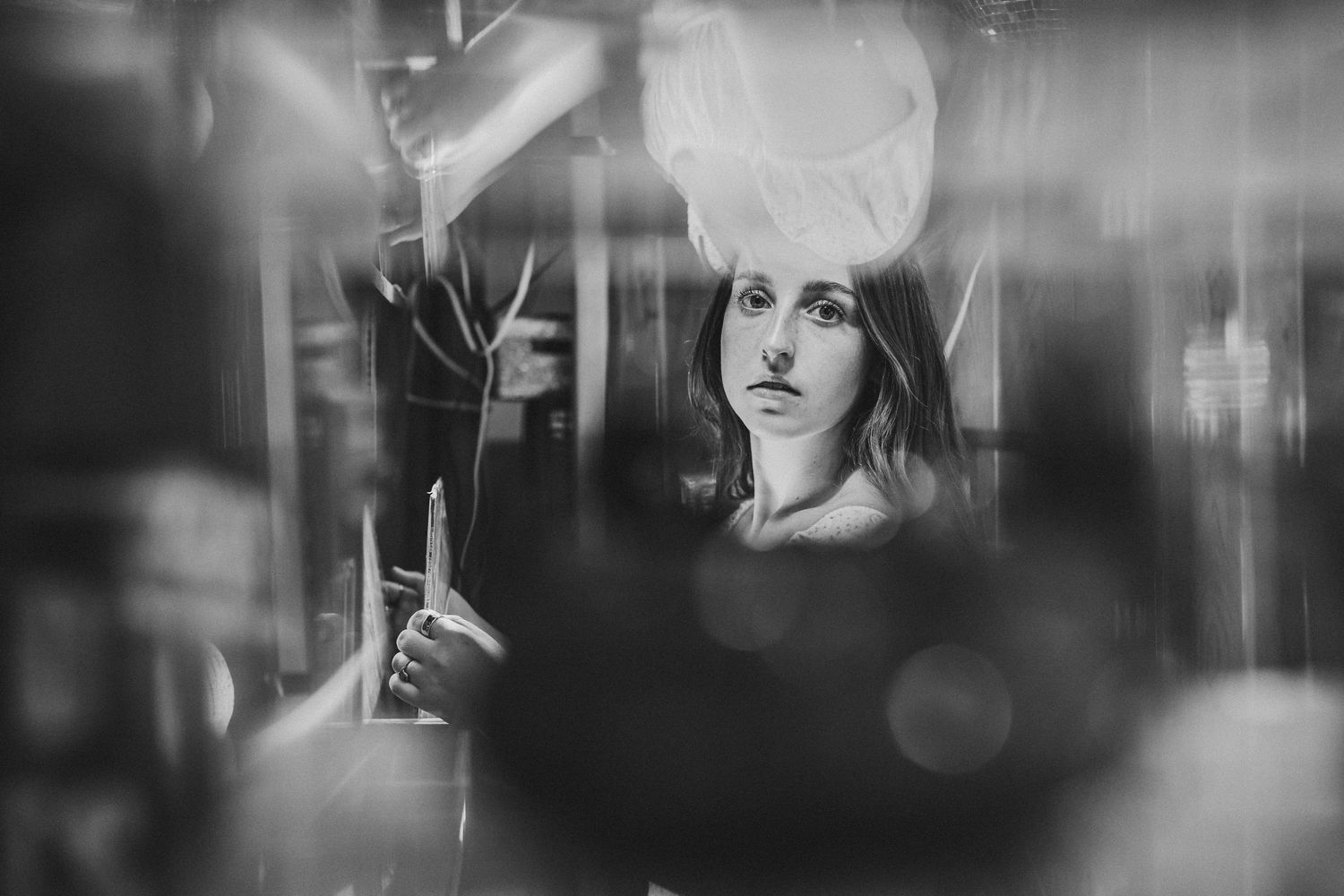A dramatic black and white portrait composition with moody lighting and reflective elements creating an artistic effect.