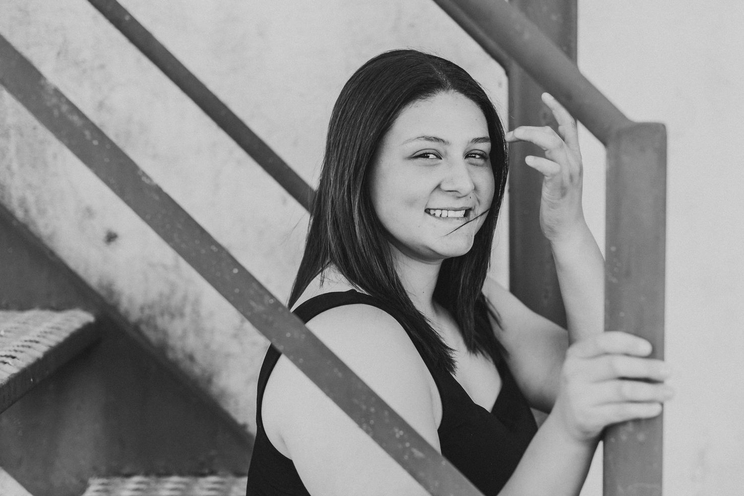 Young woman smiling on stairs in black and white portrait photo.