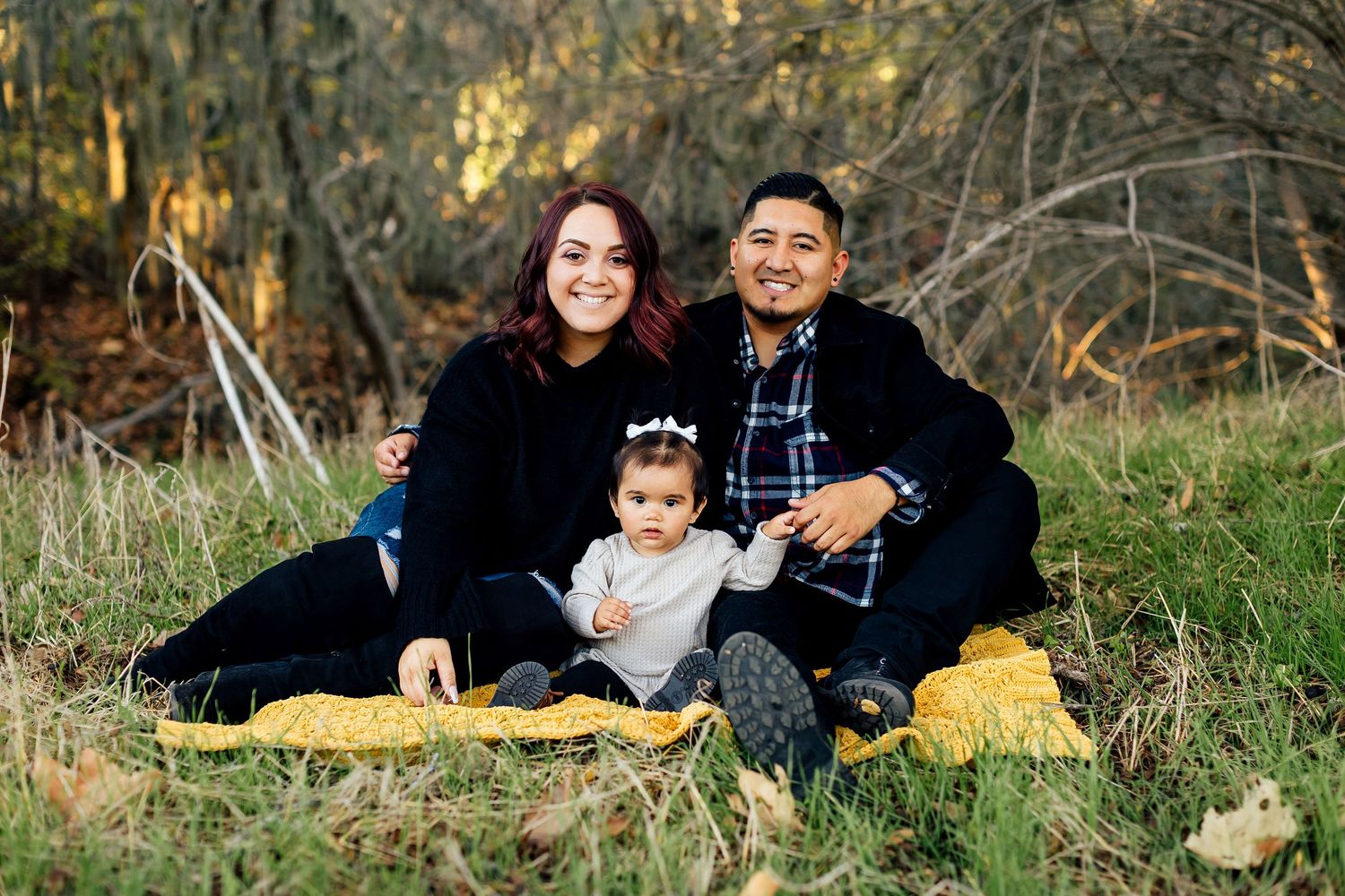 A family lying together on grass during an outdoor autumn photoshoot session in nature.