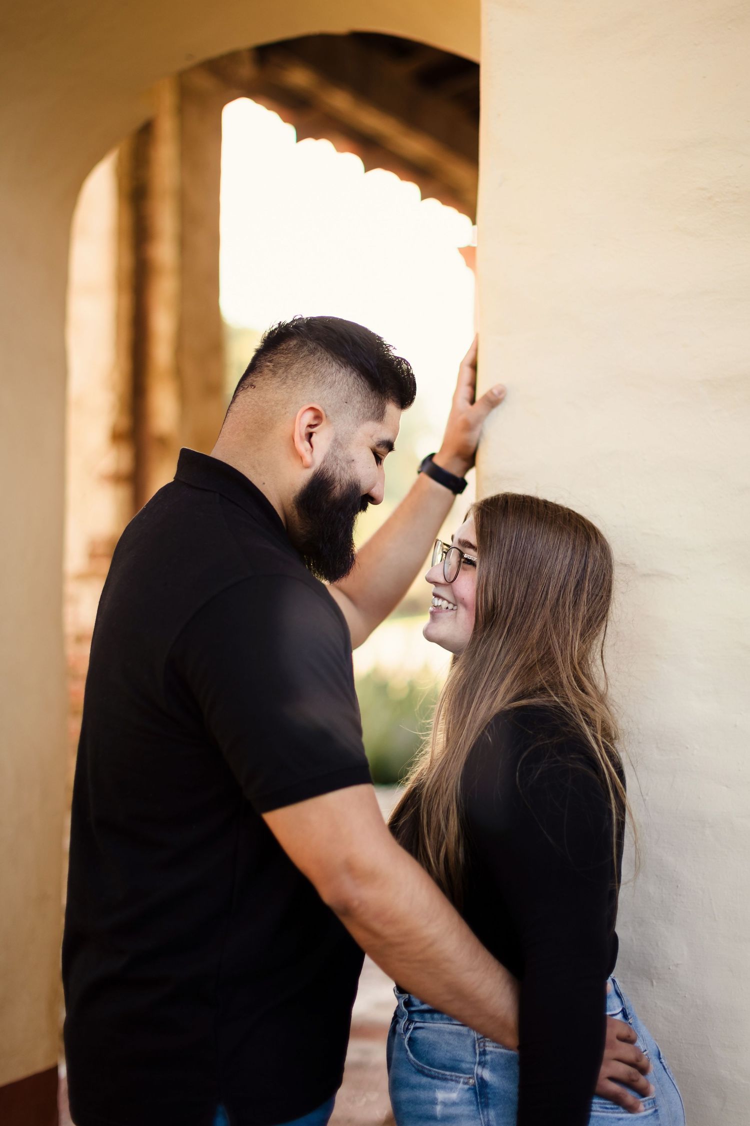 Romantic couple in black and denim share intimate moments in a series of candid poses along a wall.