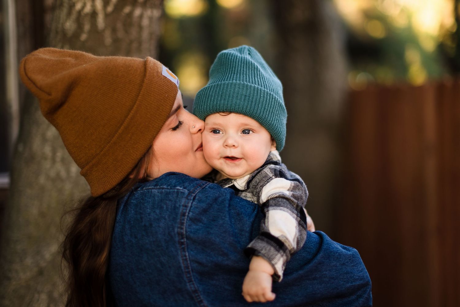 A tender moment captured outdoors during golden hour between two people wearing winter knit beanies.