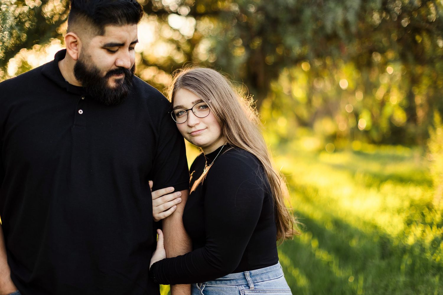 A couple shares tender moments in a sunlit forest setting during their autumn engagement photo session.