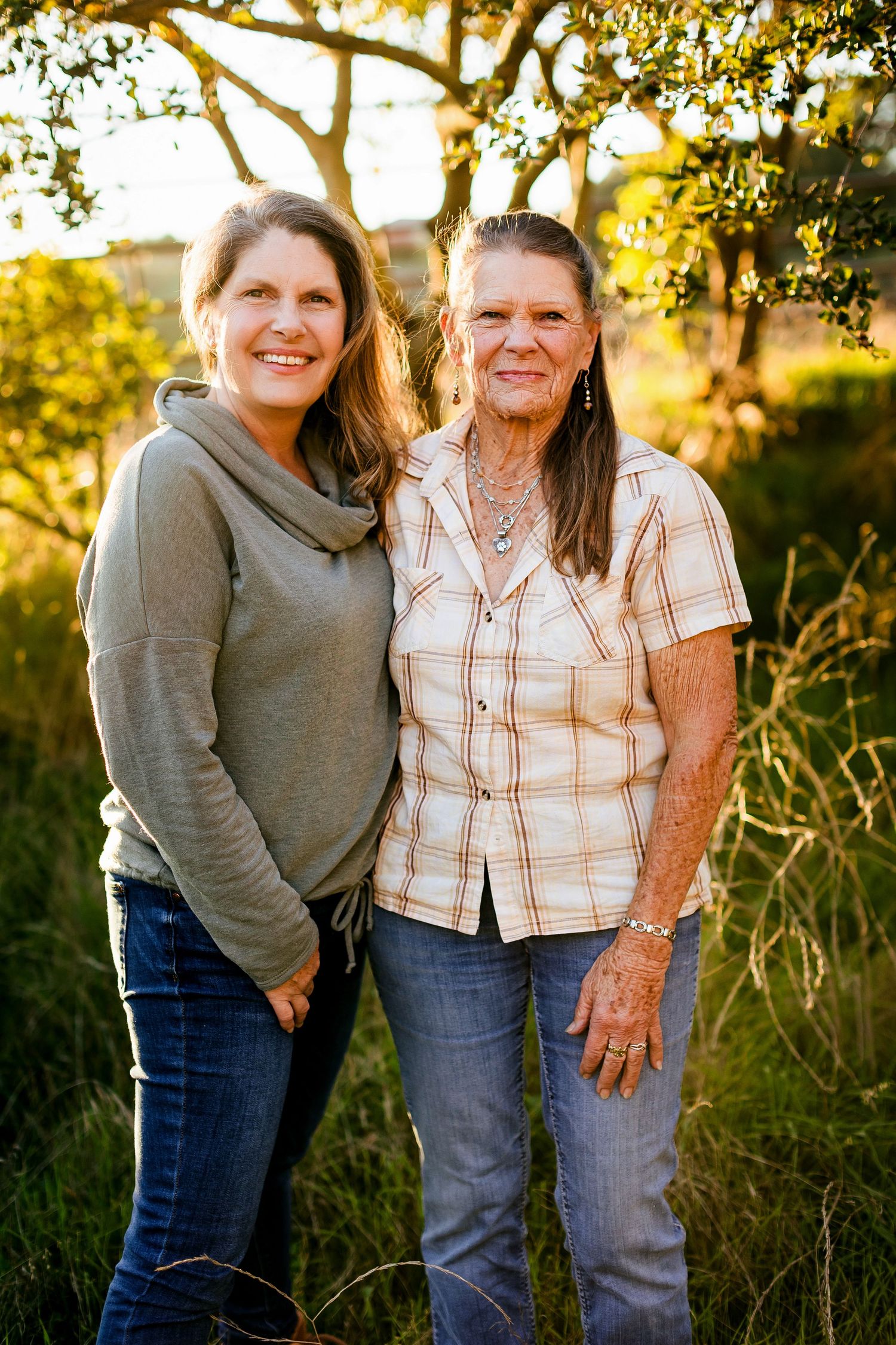 Two people share a candid laugh while standing together outdoors during golden hour sunset lighting.