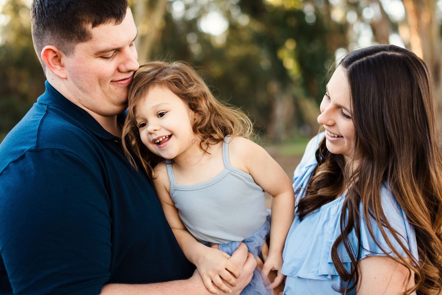 A family shares joyful moments together outdoors during a professional photo session in natural lighting.