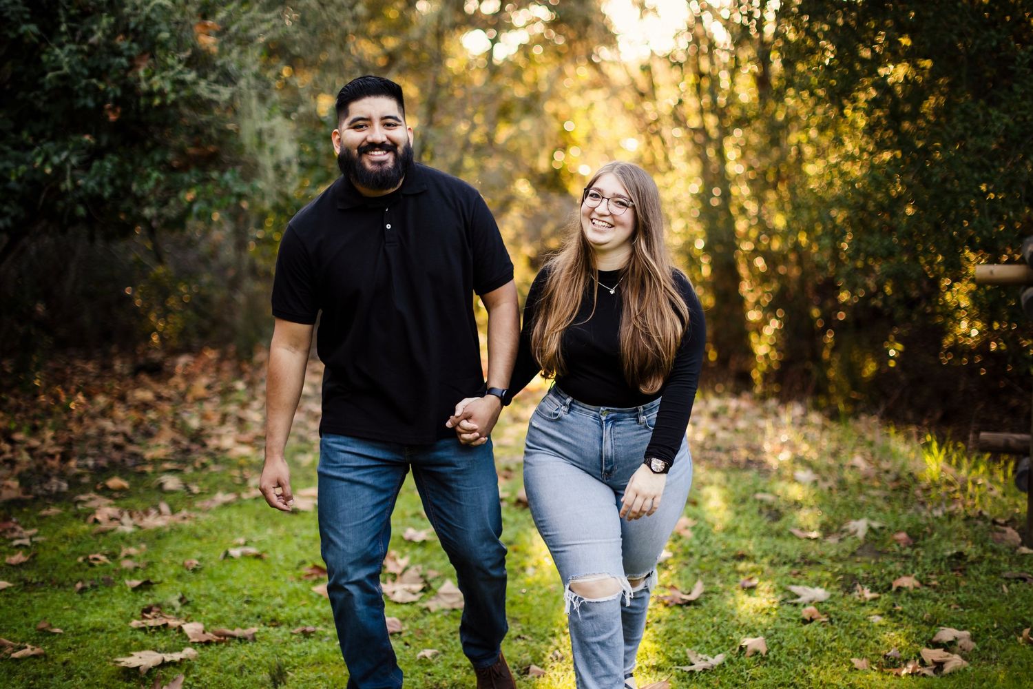 A couple walks together through a sunlit autumn forest during golden hour, enjoying a romantic moment.