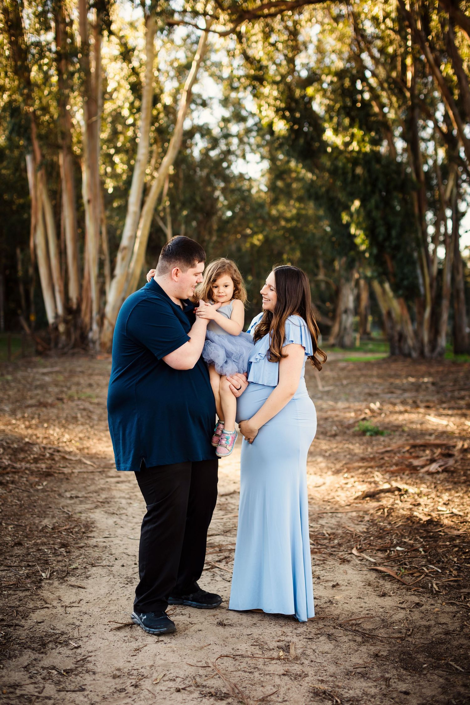 Family members in matching navy and light blue outfits share joyful moments together in a wooded outdoor setting.
