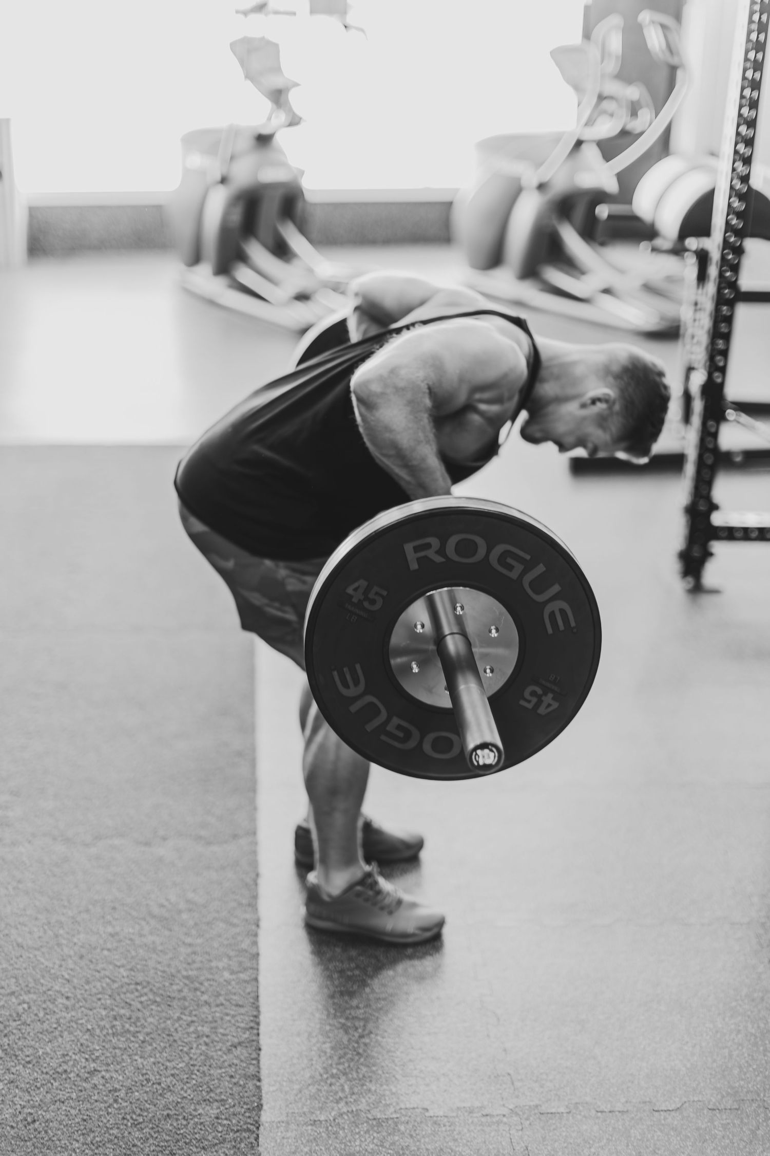 Black and white photo of athlete performing barbell deadlift exercise in gym setting.