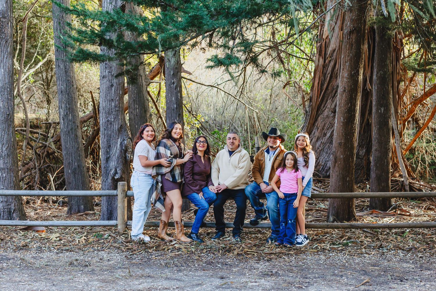A family walks together on a wooded trail surrounded by tall eucalyptus trees on a sunny day.
