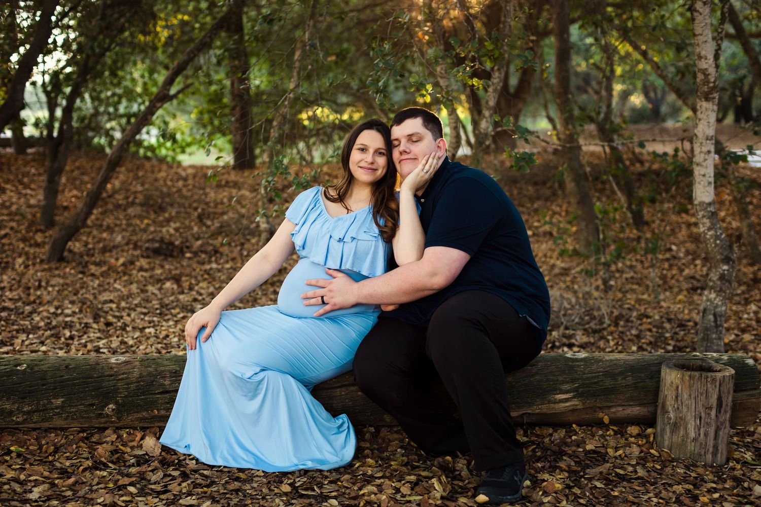 A romantic outdoor photoshoot capturing intimate moments between a couple in a wooded setting with natural lighting.