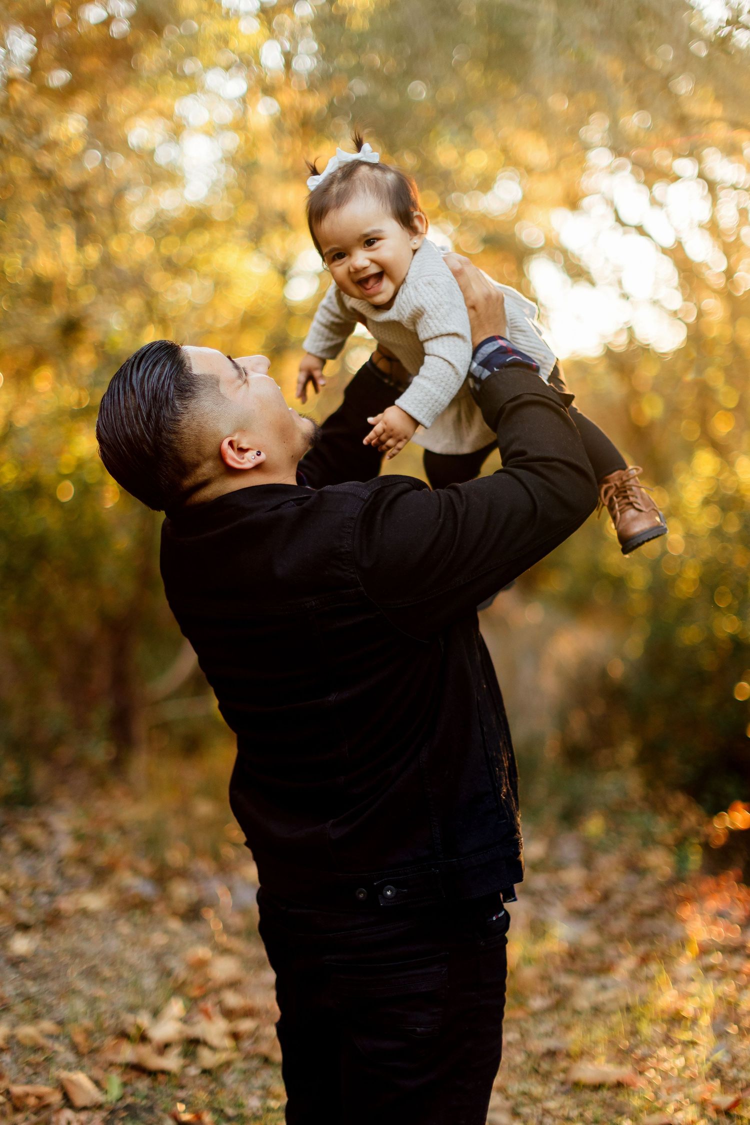 A heartwarming autumn scene shows joyful interaction between parent and child amidst golden foliage and warm sunlight.