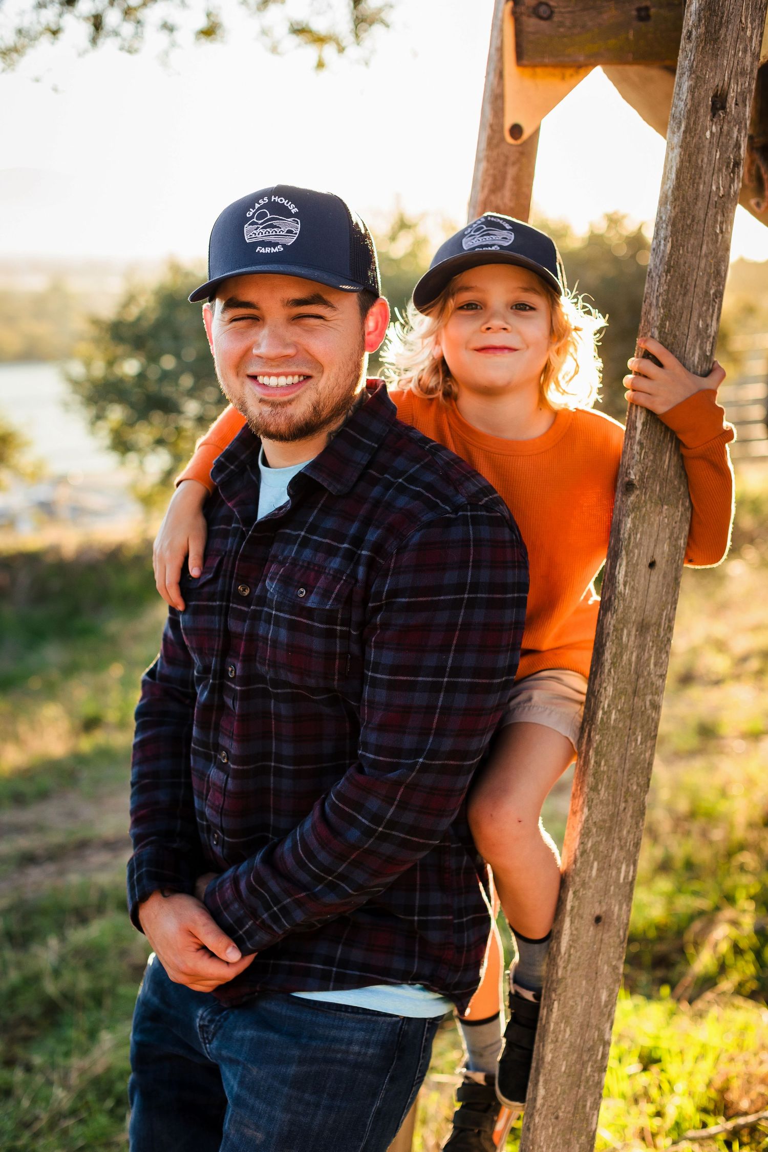 A family sits on wooden posts at sunset capturing a series of candid poses in outdoor autumn portraits.