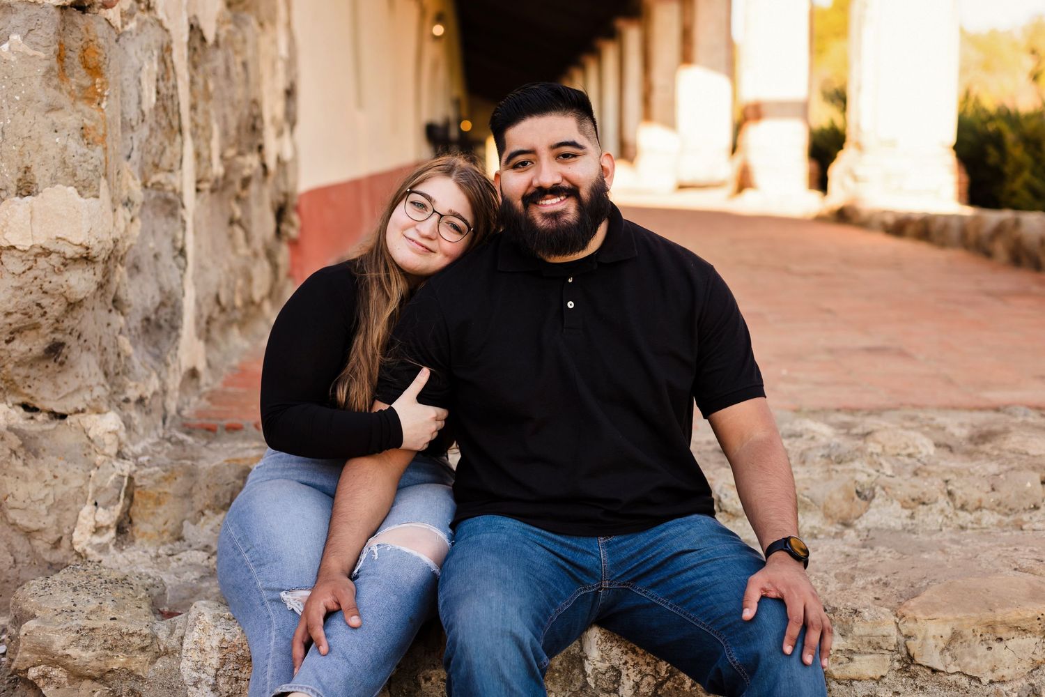 A couple sitting together on stone steps share warm moments in various poses during an outdoor photo session.