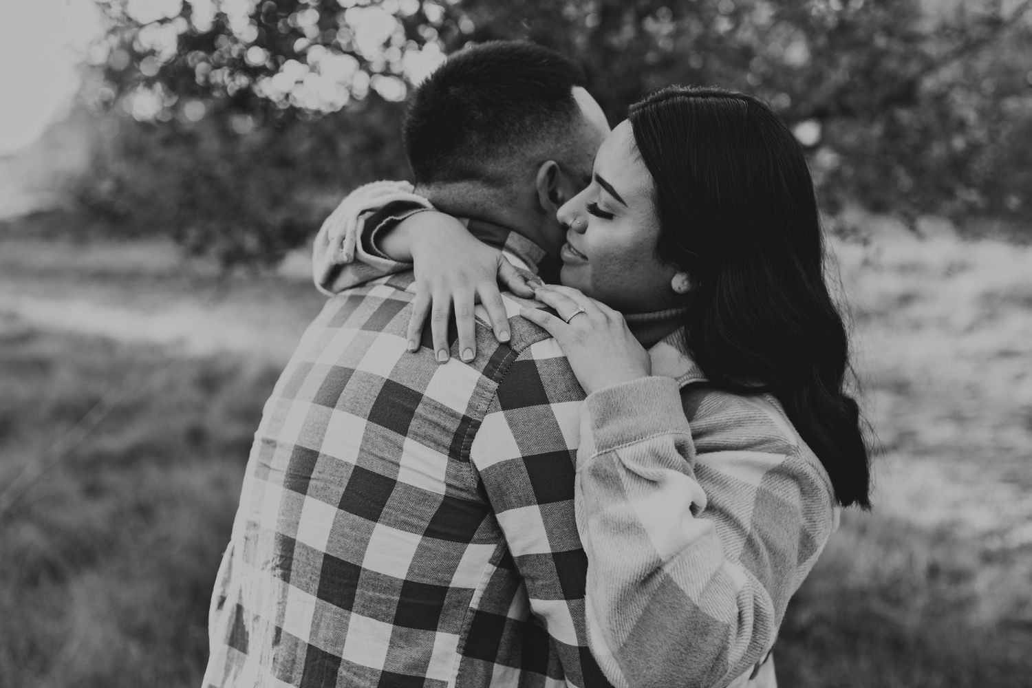 A romantic black and white photo shows an intimate embrace between a couple in an outdoor setting.