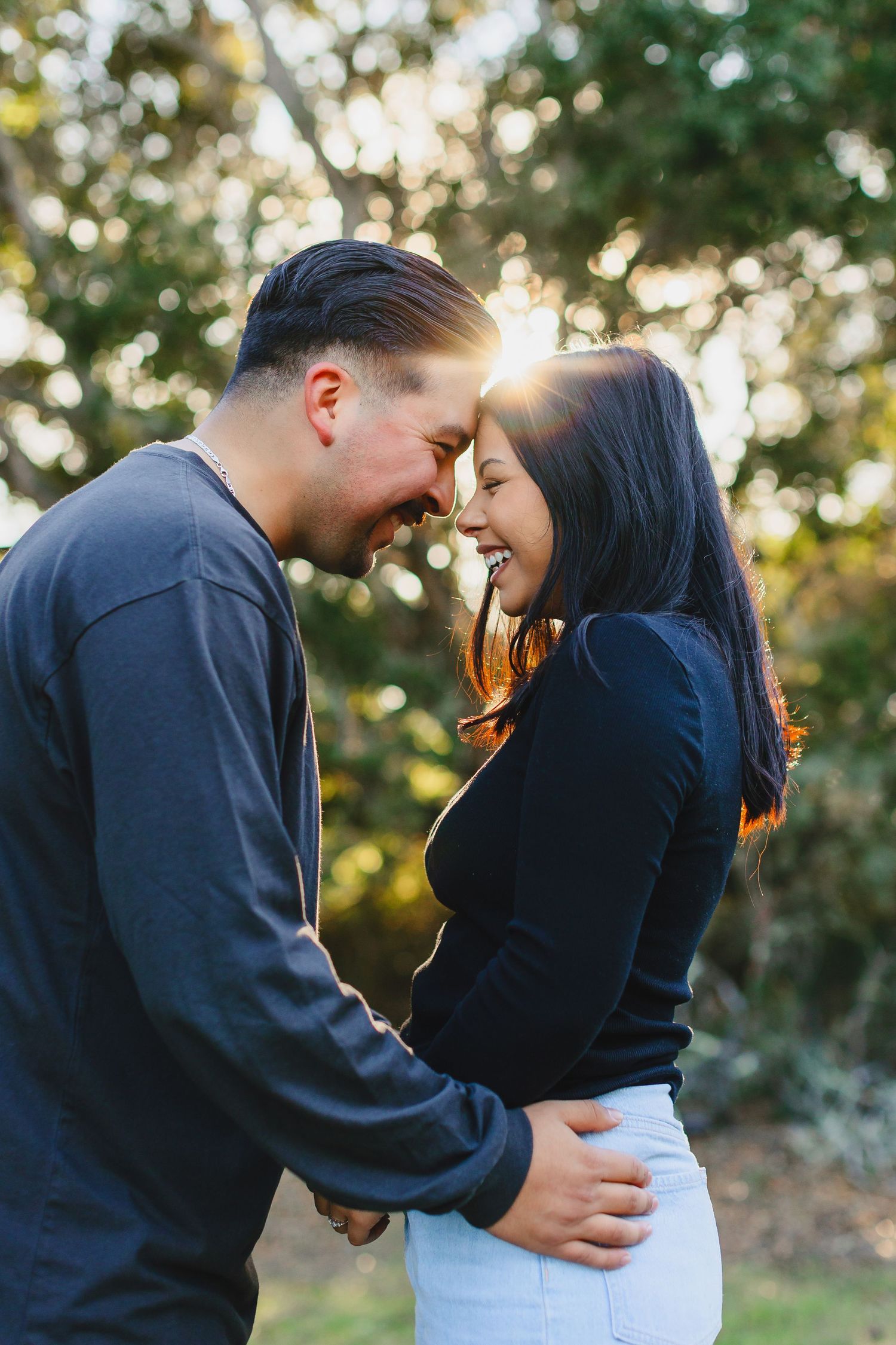 A romantic couple shares an intimate moment while embracing in golden sunset light.