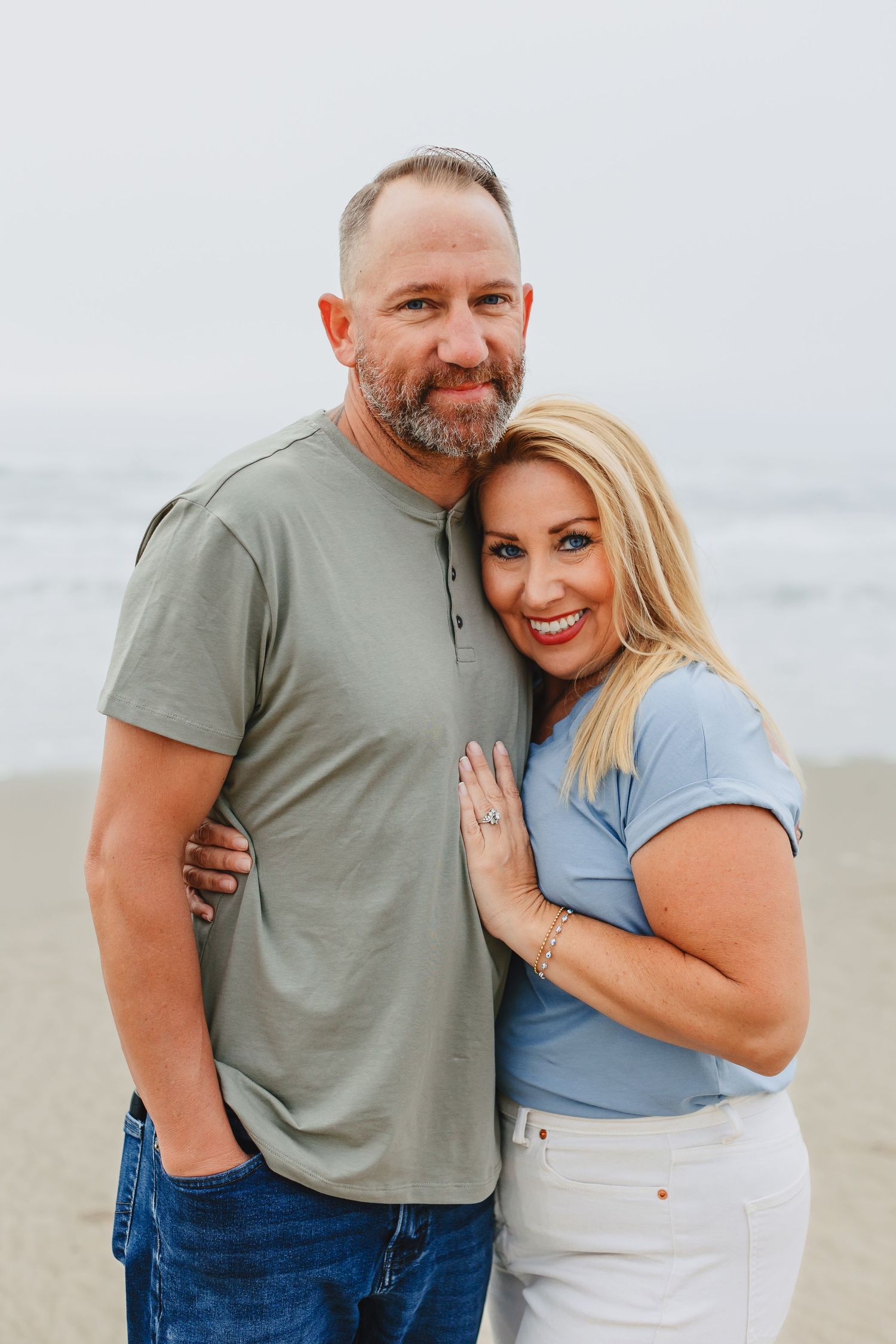 A casual couple posing together on a misty beach.