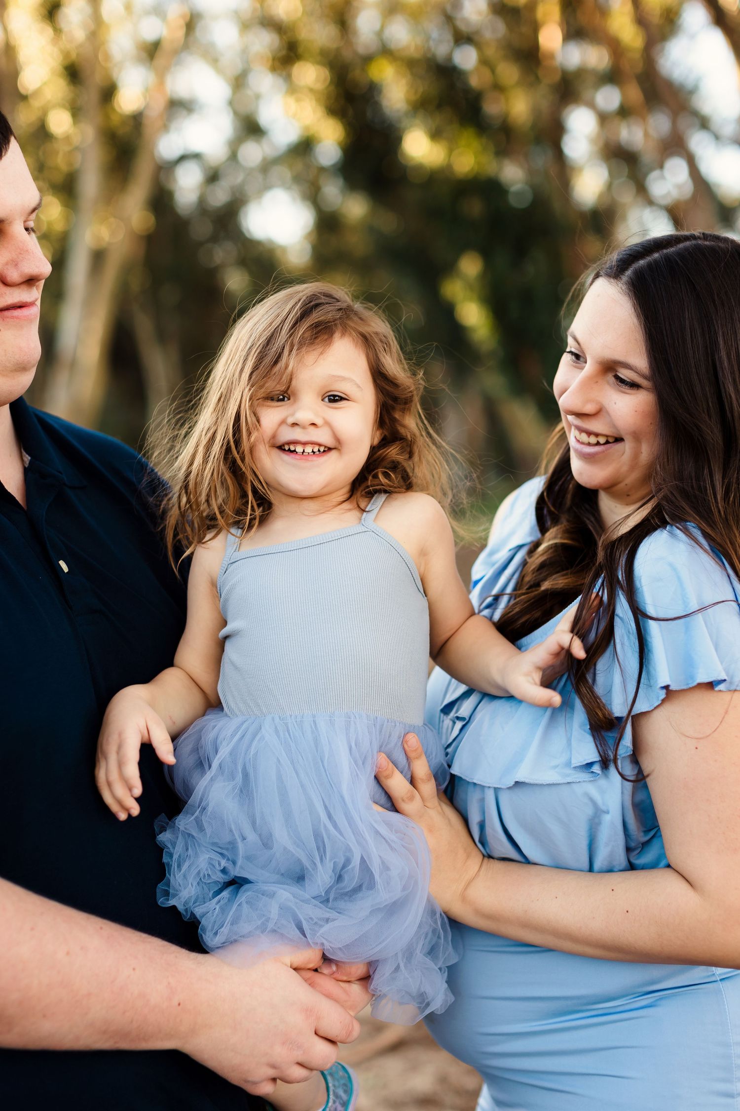 A series of candid shots showing joyful interaction between family members wearing light blue outfits in an outdoor setting.