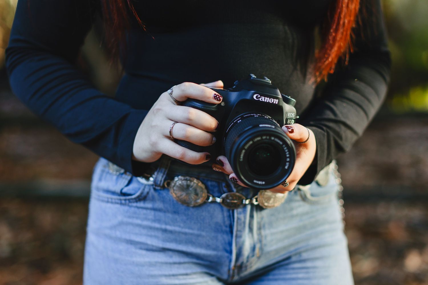 A close-up sequence showing hands holding a camera against blue jeans in natural outdoor lighting.