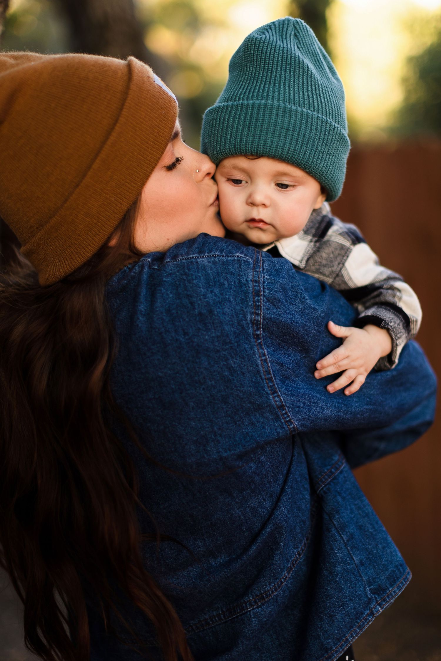 Tender outdoor moment in autumn showing an embrace while wearing cozy knit beanies at golden hour.
