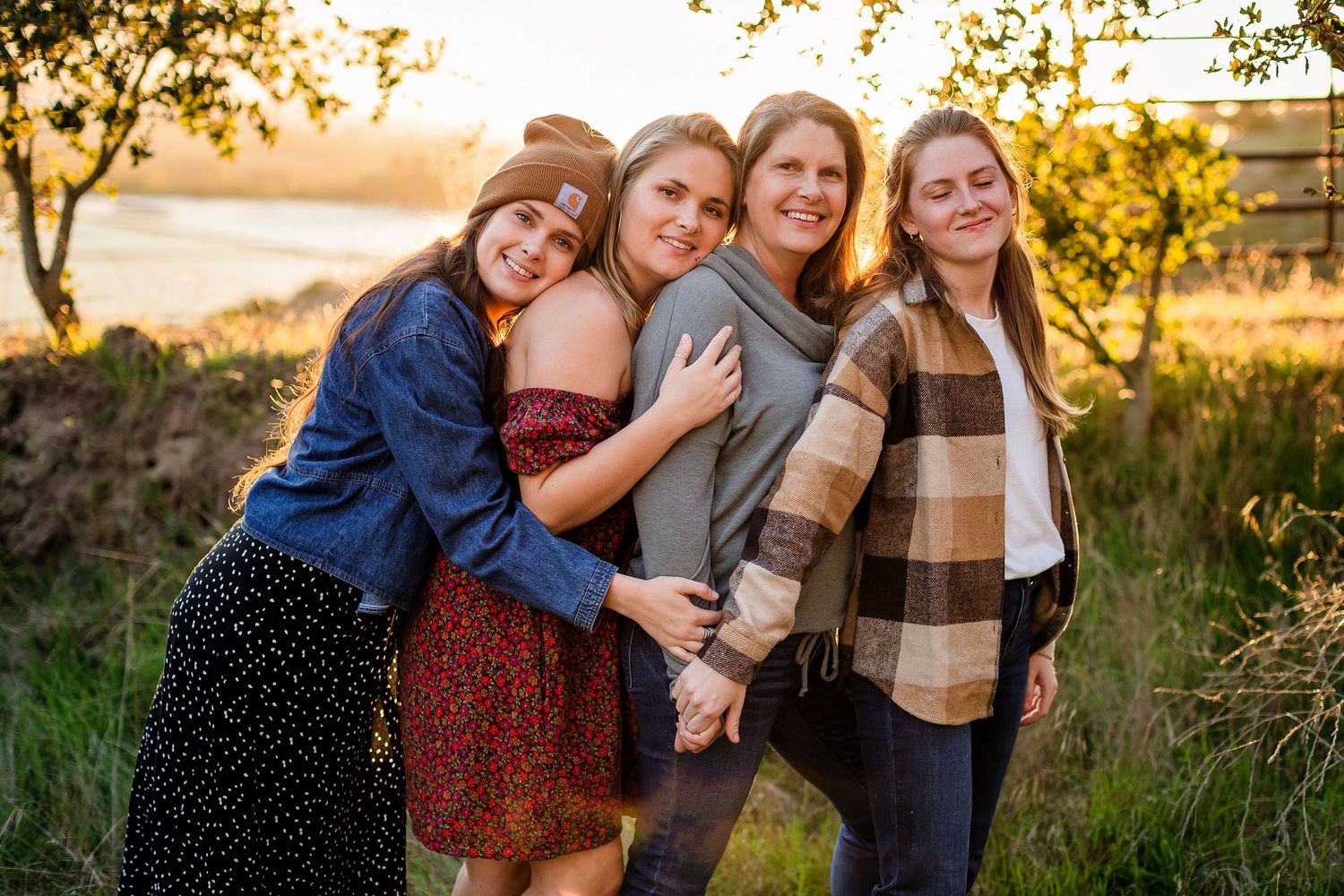 Casual group poses together during golden hour photo session in rustic outdoor setting at sunset.