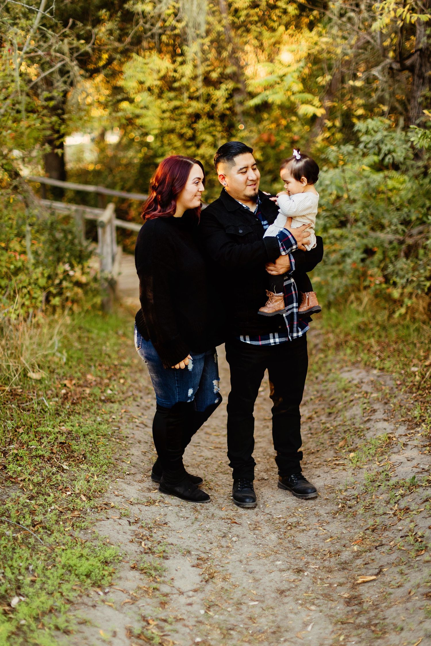 Family plays on a wooded forest path during a photography session in beautiful autumn scenery.