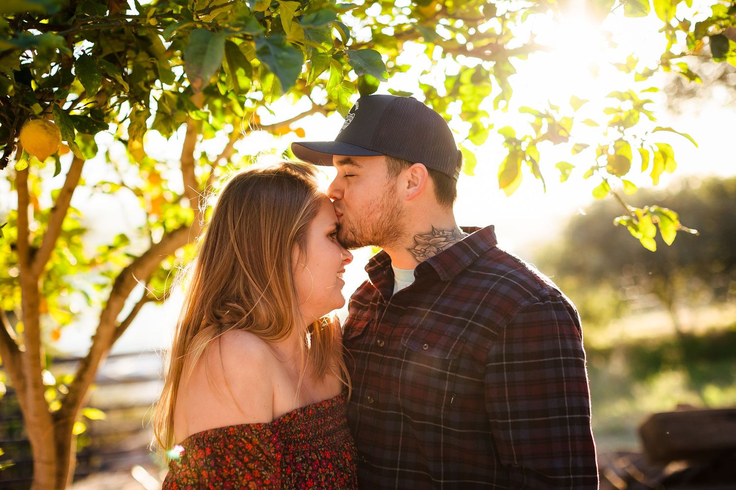 A couple sharing a romantic moment in a sun-dappled garden path with golden sunlight filtering through tree leaves.