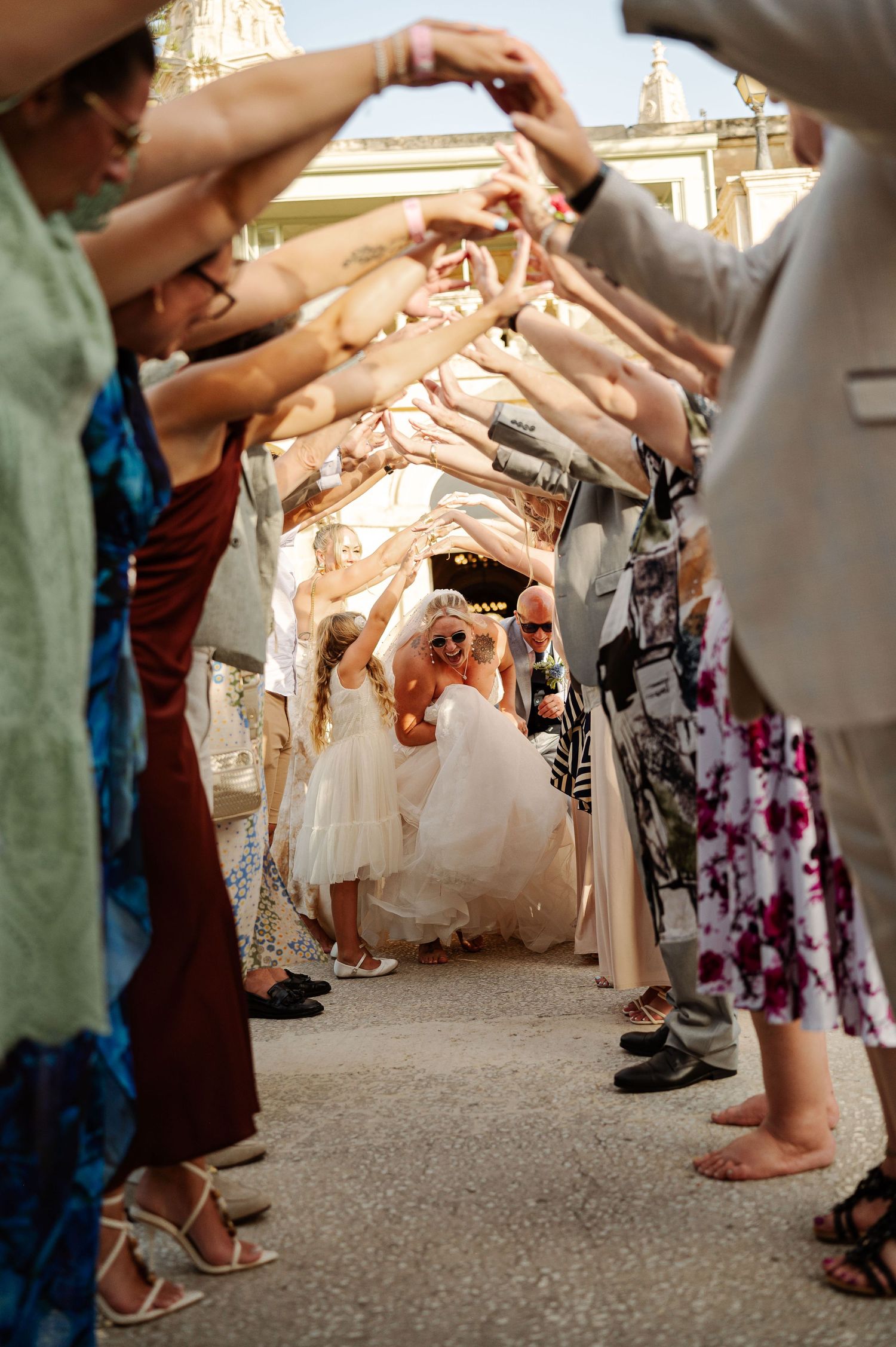 People's feet and legs gathered in a circle on a carpeted floor during what appears to be a wedding or formal event.