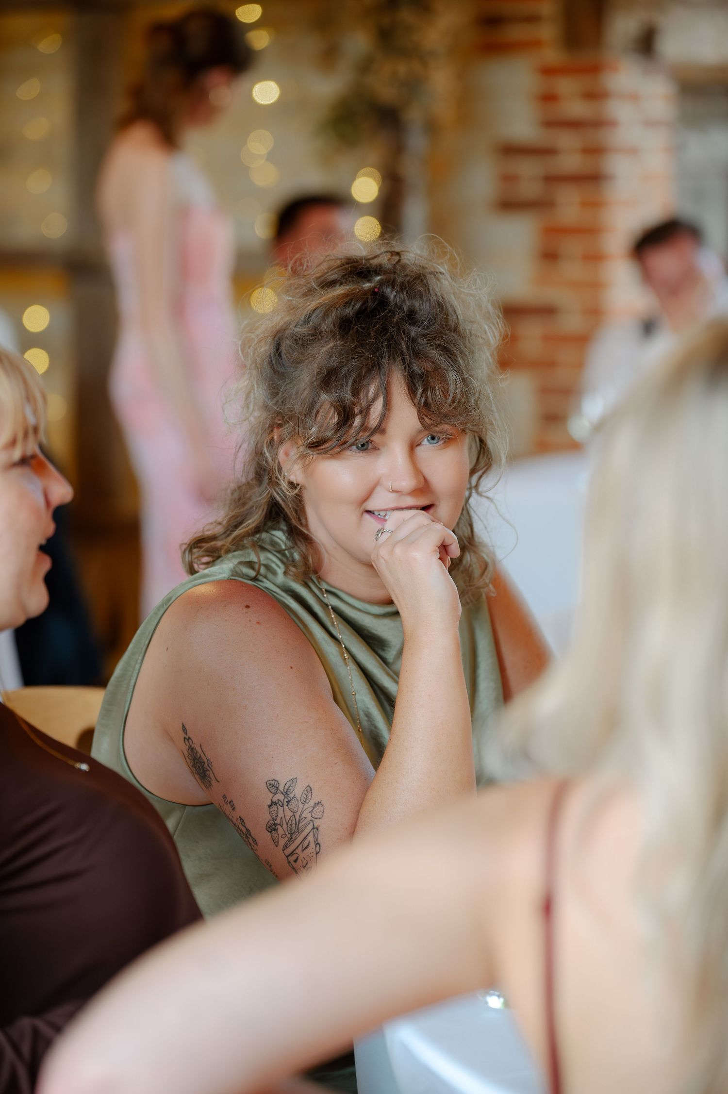 Wedding guests in casual attire gather at a reception with warm lighting and blurred background.