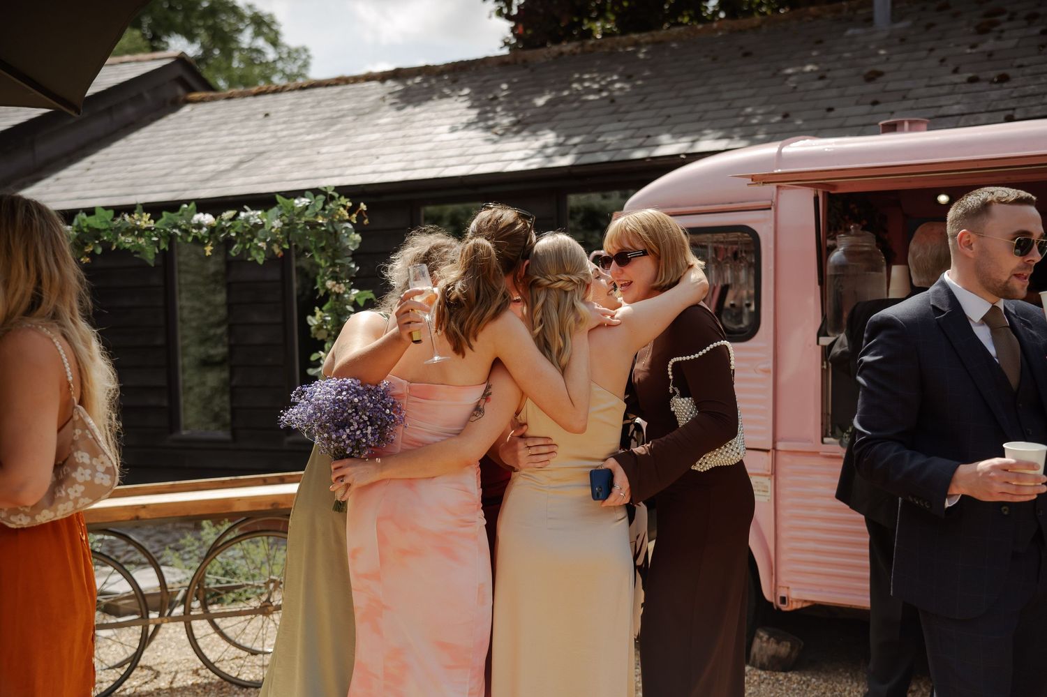 Wedding party members celebrate and dance together in a candid outdoor reception moment.