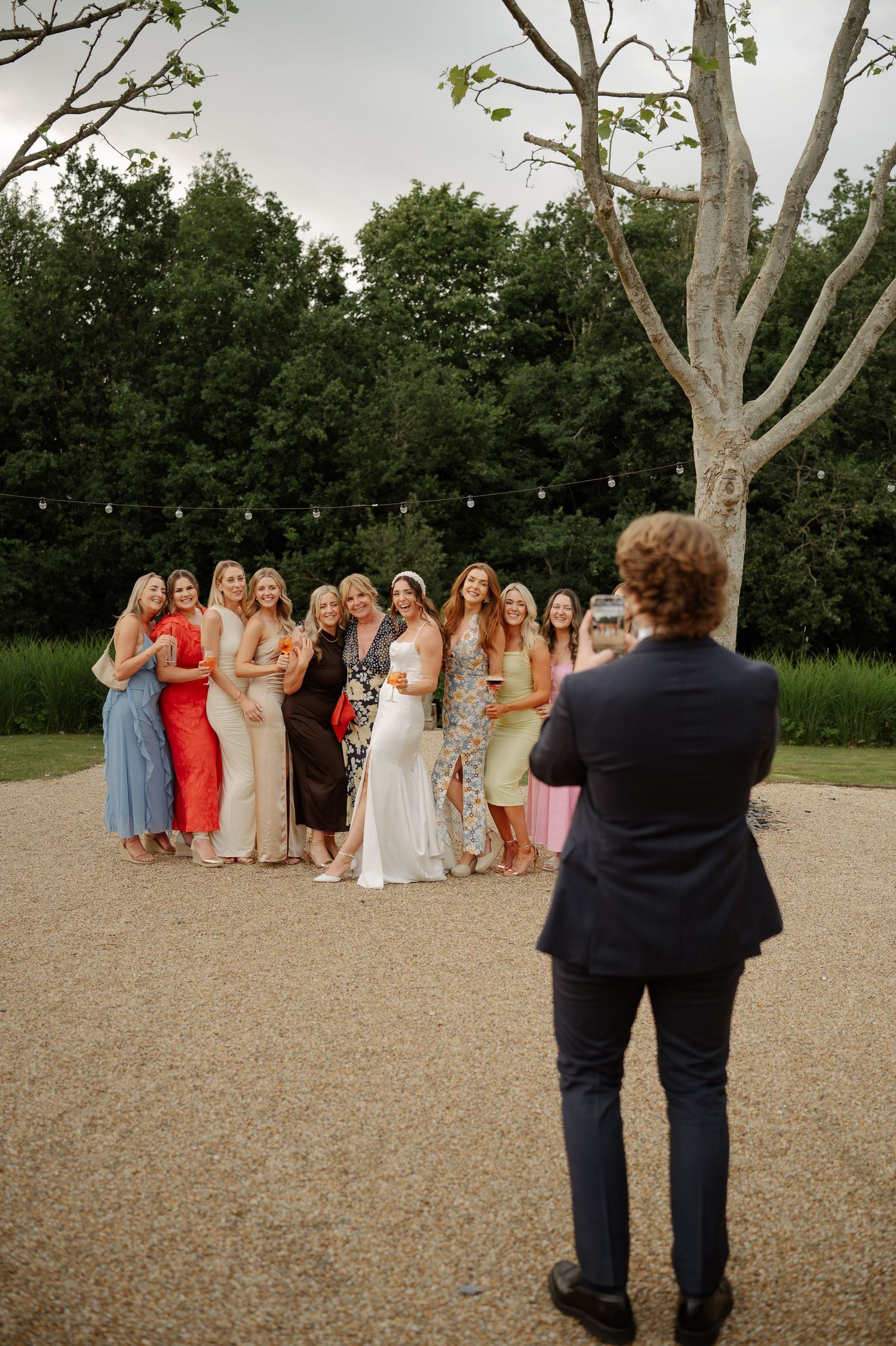 Wedding photographer captures group photo of guests outdoors.