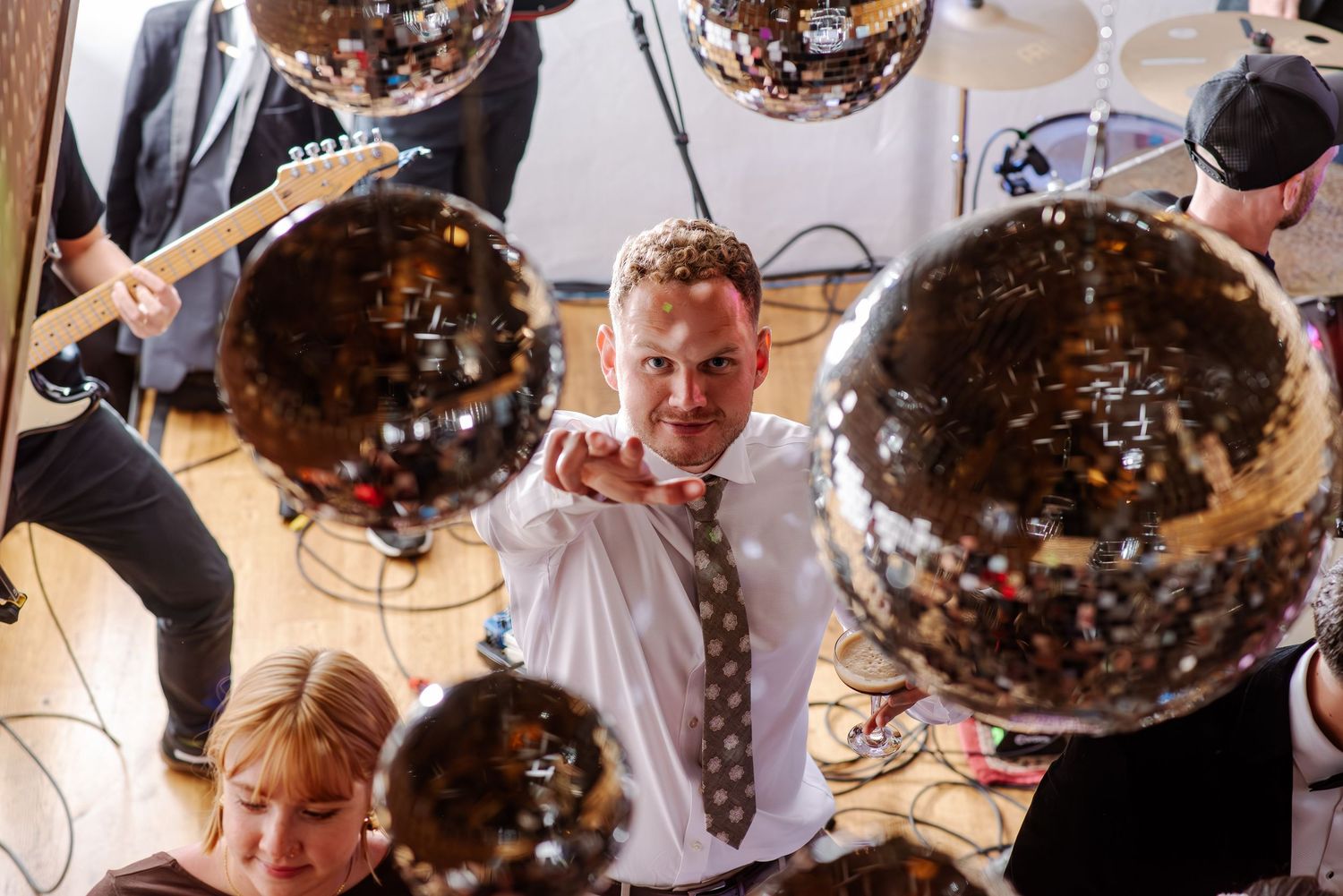 Disco balls hang from ceiling with colorful party lights creating a festive dance floor atmosphere.