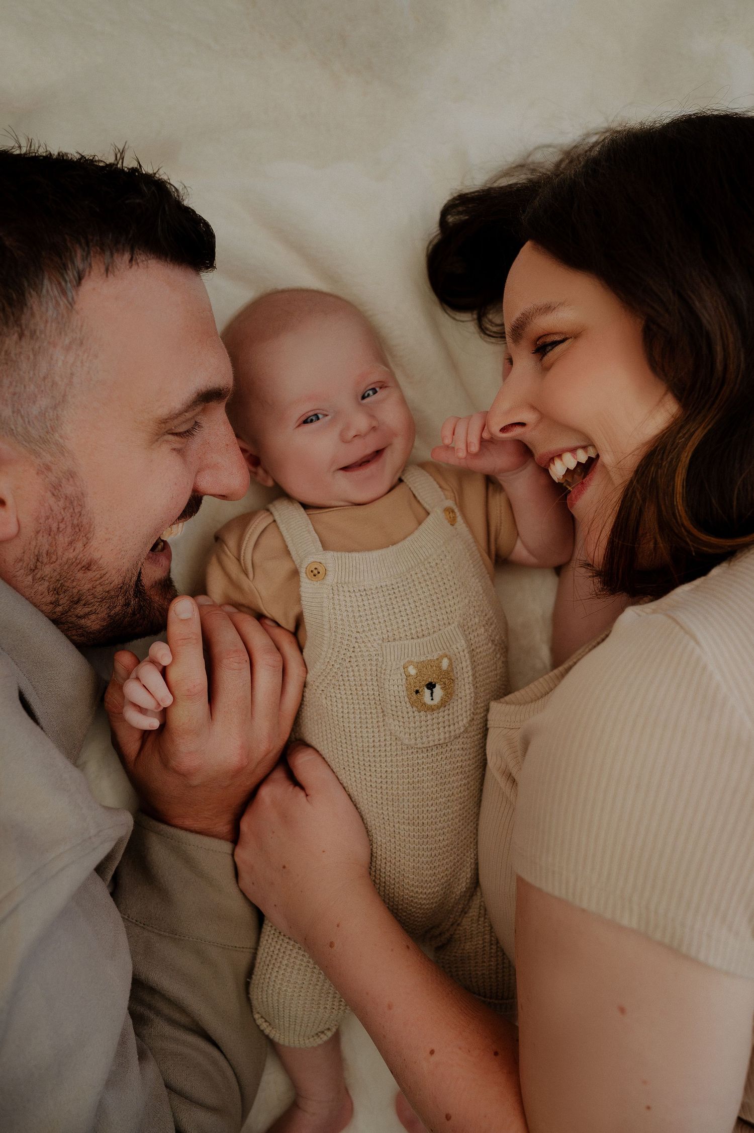 A loving family shares tender moments and laughter while snuggling close together in matching cream colored sweaters.