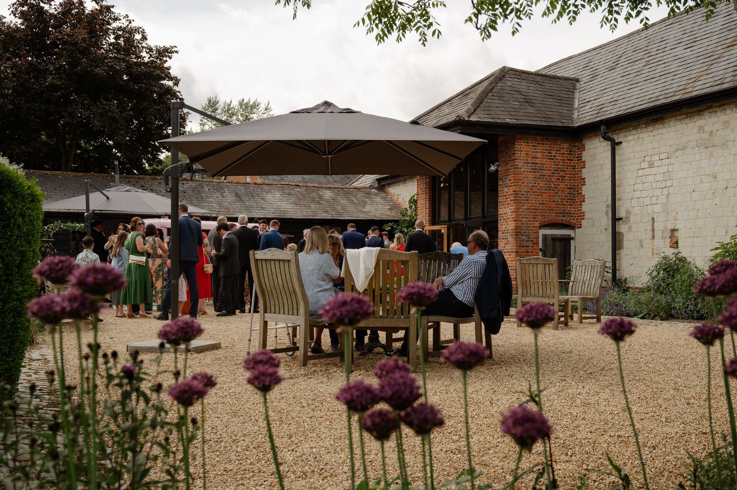Rustic barn venue decorated with hanging purple flowers and outdoor seating for a wedding reception.