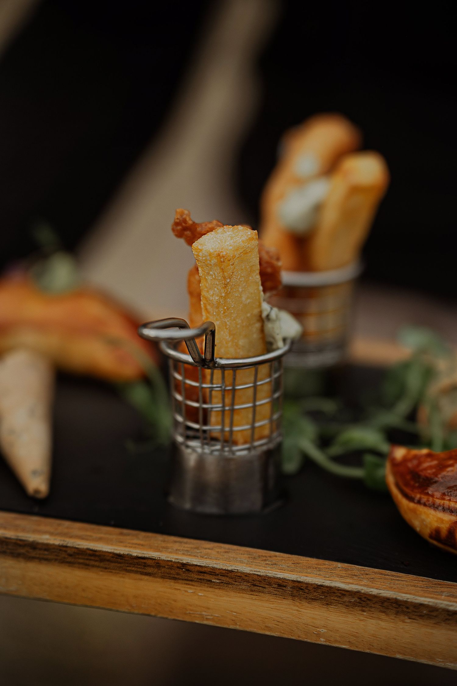Close-up shot of grilled cheese sandwiches served in metal holders on a rustic wooden board.