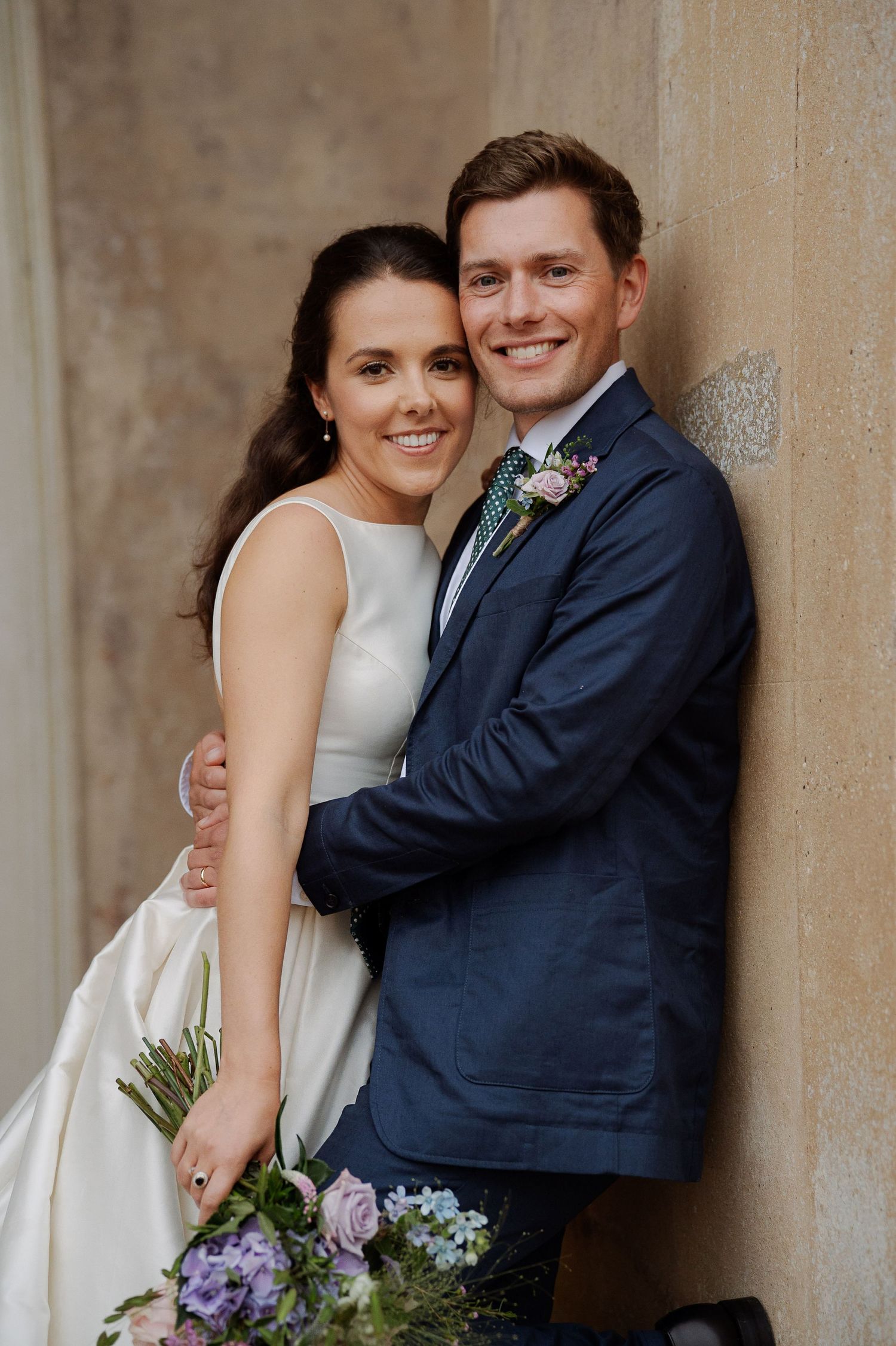 A bride and groom share intimate moments in a series of romantic wedding portraits against a stone wall.