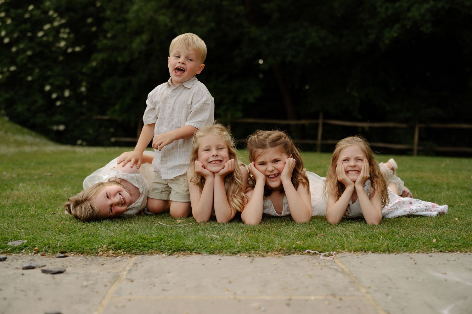 Children lying down and posing playfully on outdoor steps.