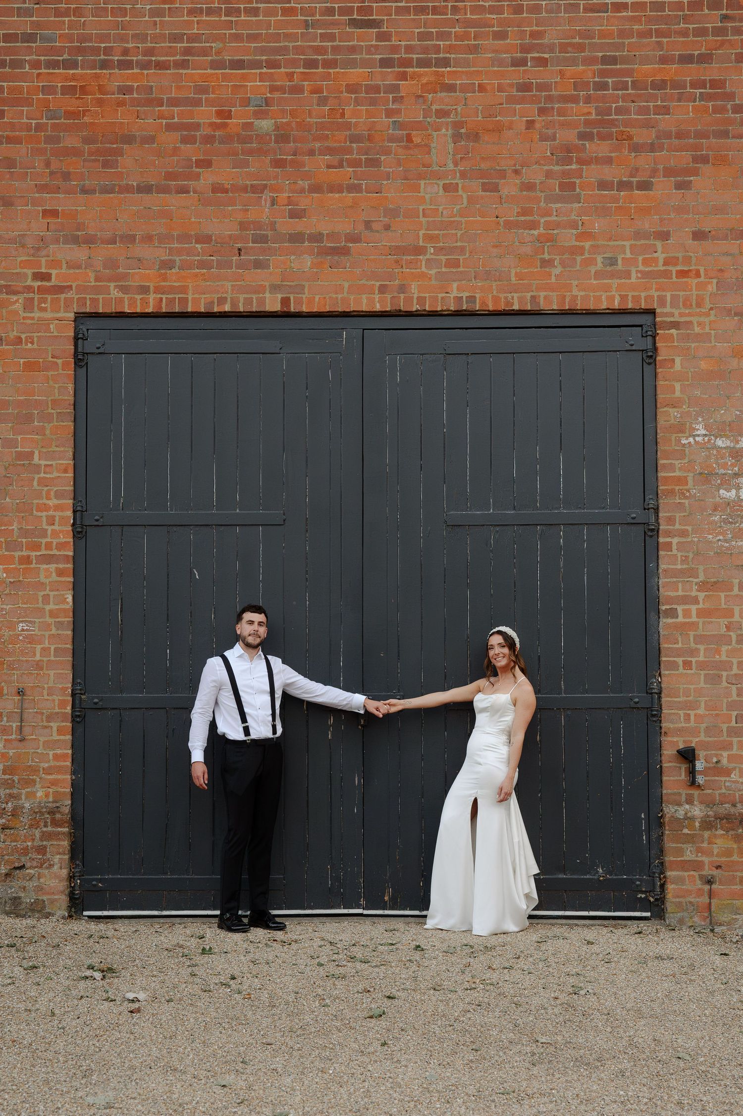 A creative wedding photo sequence showing a couple playfully interacting across black garage doors against a brick wall.