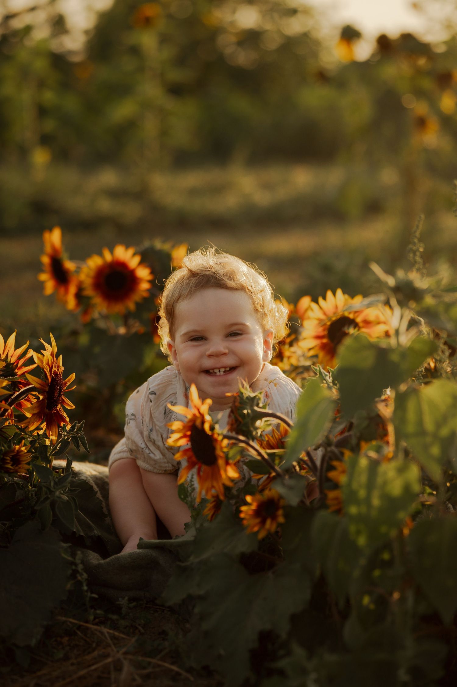 A joyful baby smiles among vibrant sunflowers in a golden sunlit field.