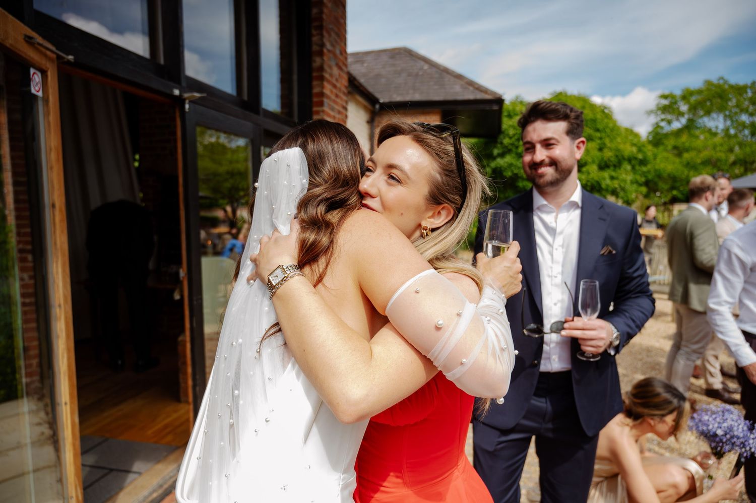 Wedding guests celebrating and embracing during an outdoor reception at a rustic venue.