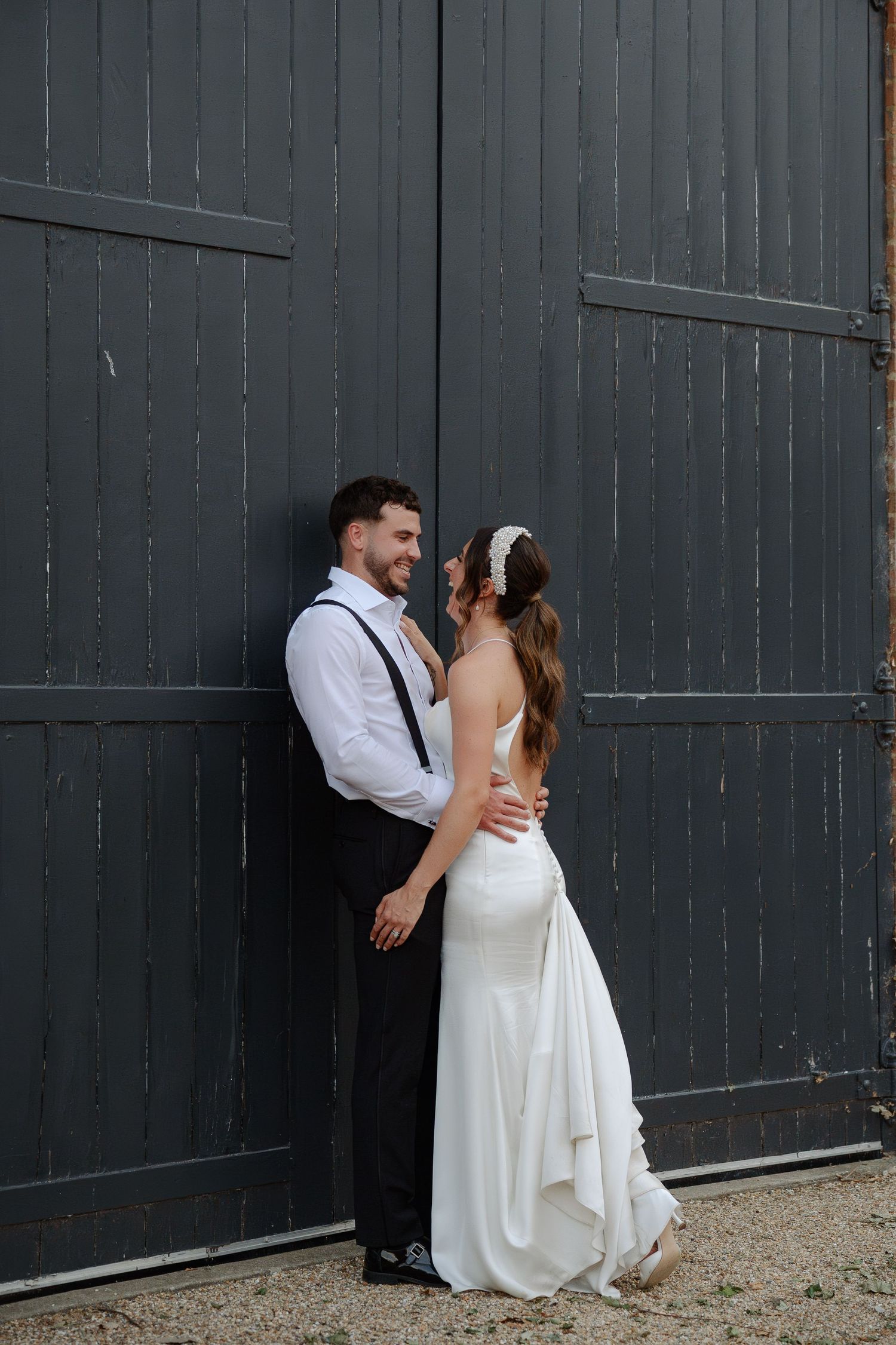Bride and groom share an intimate moment against a dark grey wooden wall.