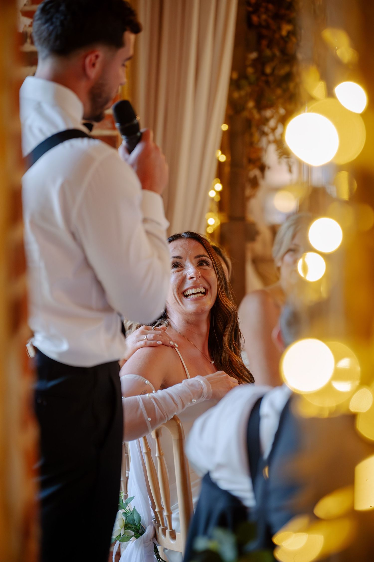 Candid wedding reception scene with warm lighting and bokeh effects creating a romantic atmosphere.