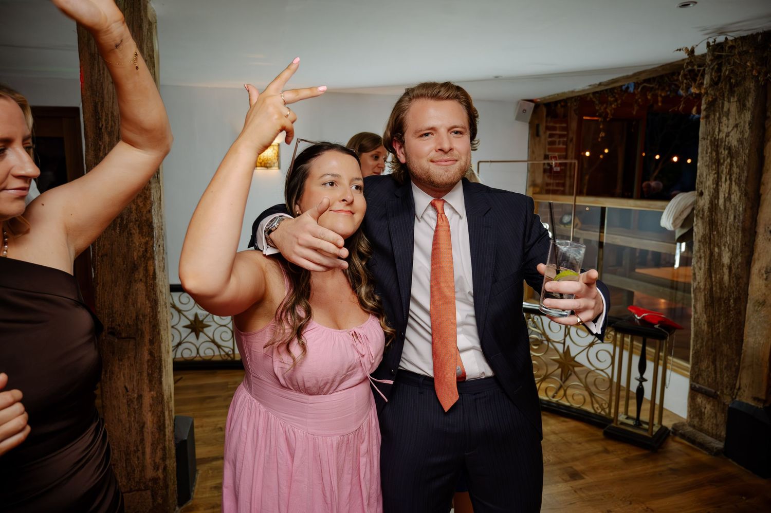 People dancing and celebrating at a rustic indoor wedding reception.