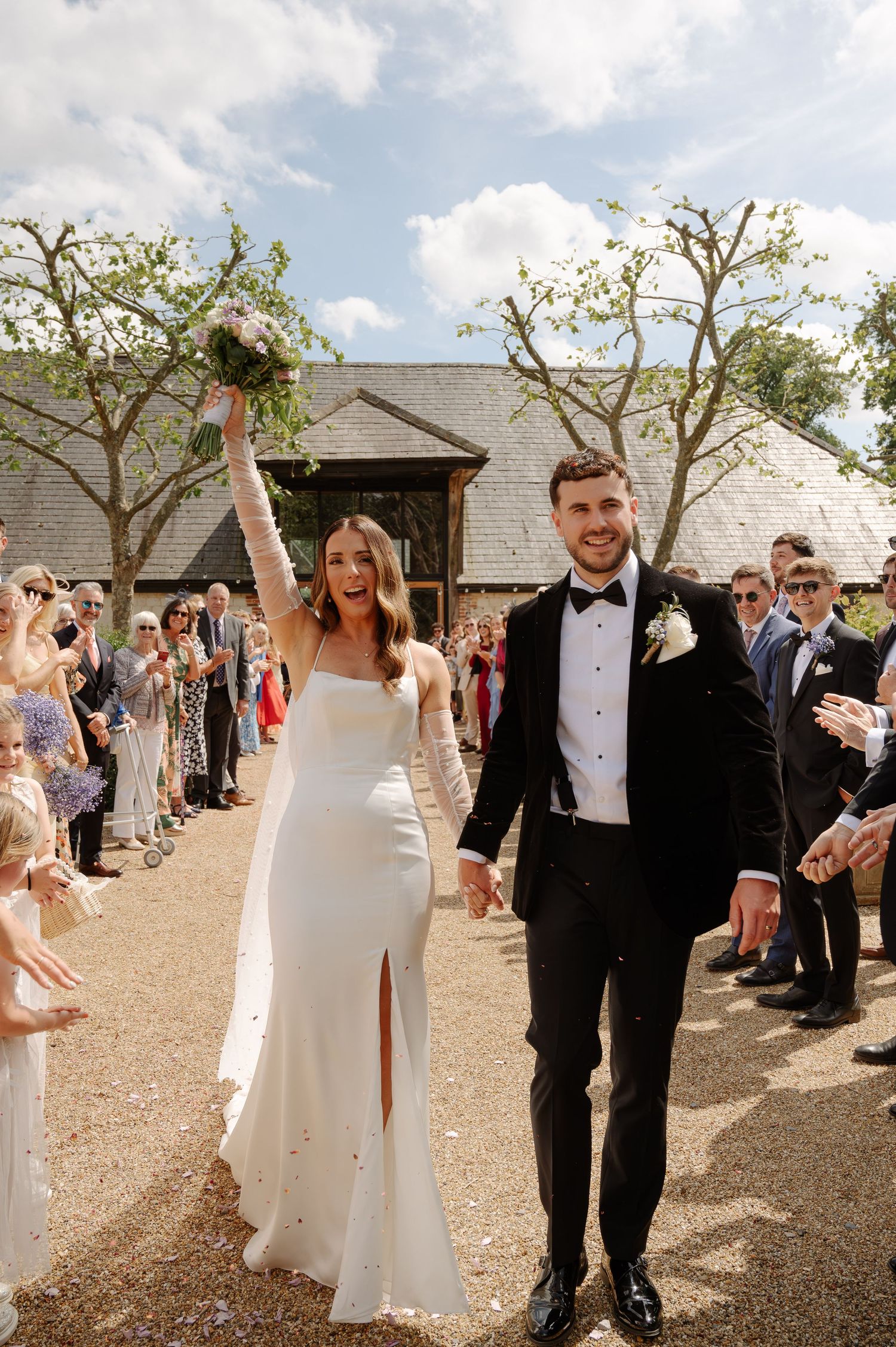 Wedding couple celebrates with guests throwing confetti during their outdoor venue exit.
