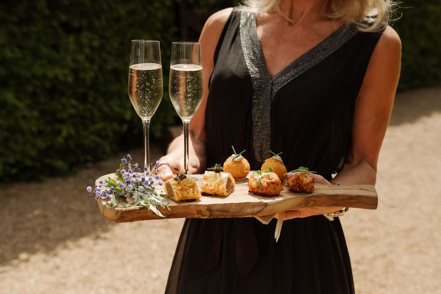 Wedding reception appetizers and champagne being served on elegant black trays.