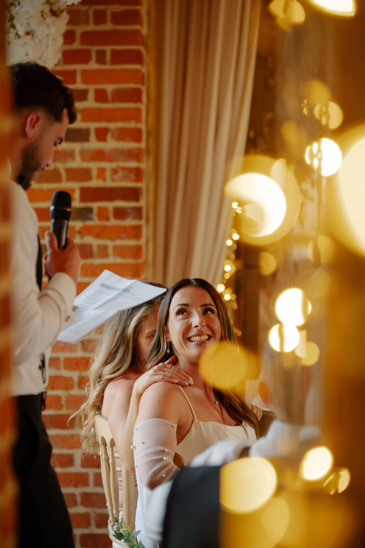 Wedding reception with glowing lights and exposed brick creating an intimate atmosphere.