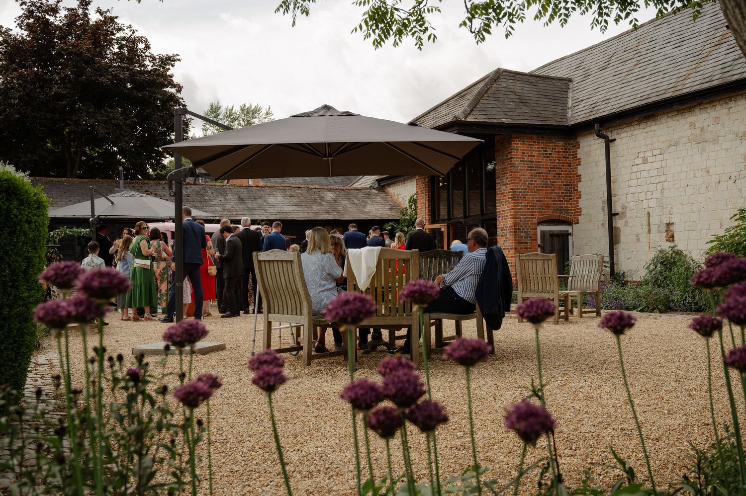 Rustic barn wedding venue with purple allium flowers decorating the outdoor courtyard area.