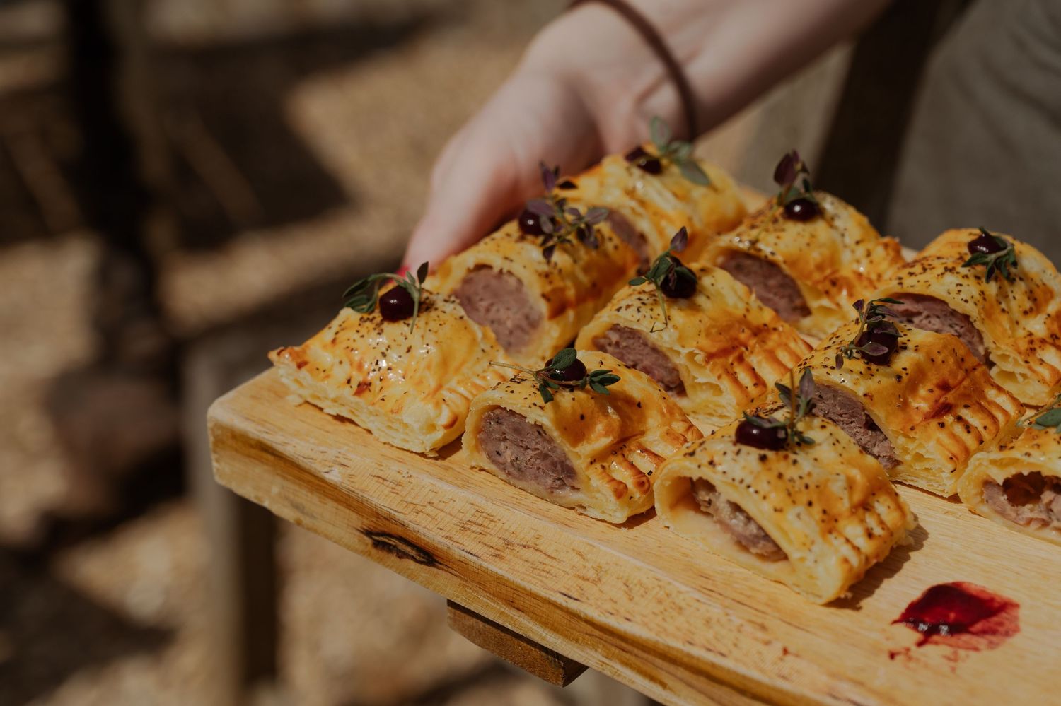 Hands arranging slices of bruschetta topped with colorful ingredients on a rustic wooden serving board.