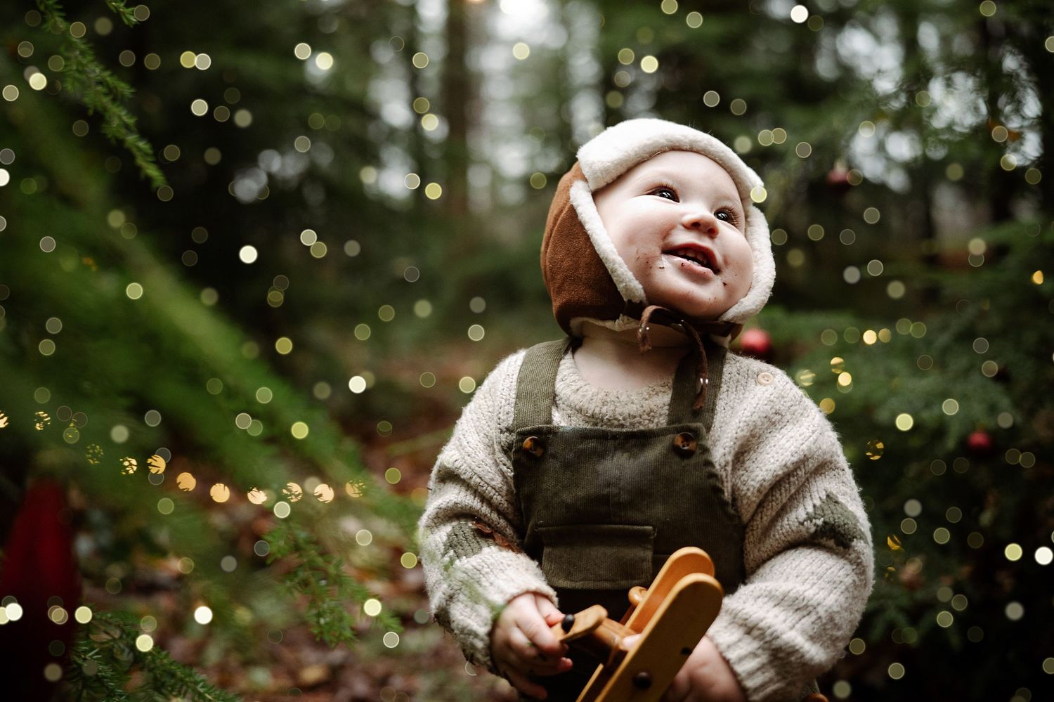 A person wearing a cozy beige sweater enjoys a magical winter moment in a snowy forest with twinkling lights.