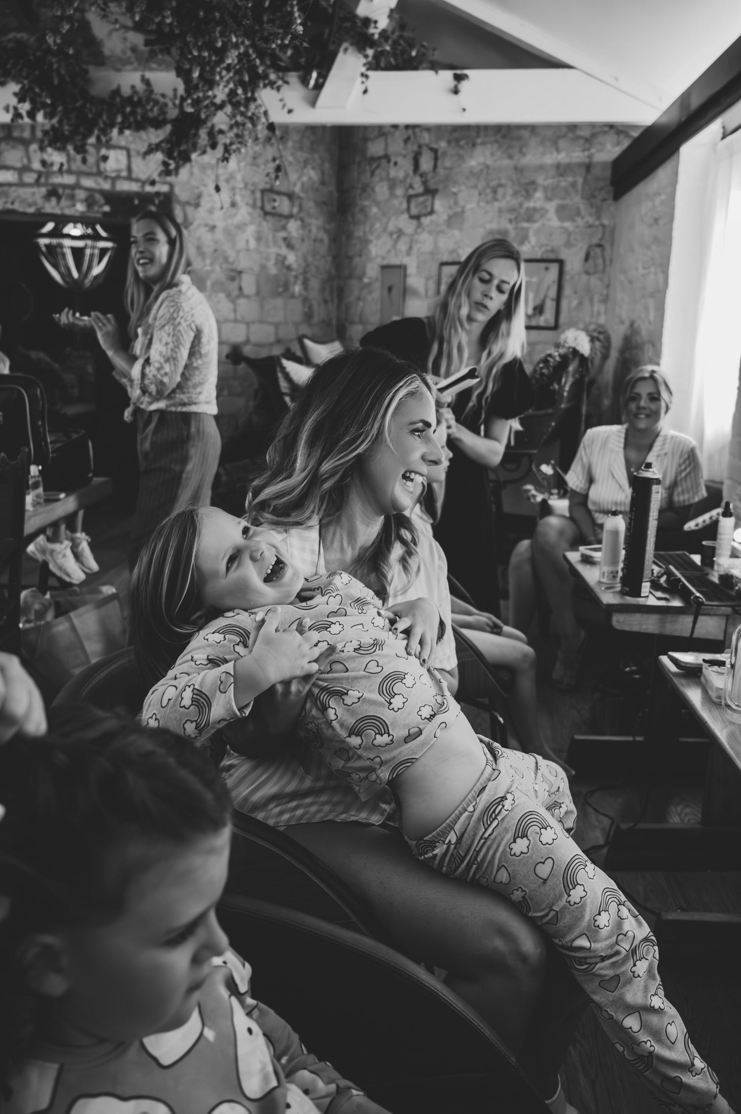 Black and white candid moments captured during wedding preparation in rustic indoor setting.