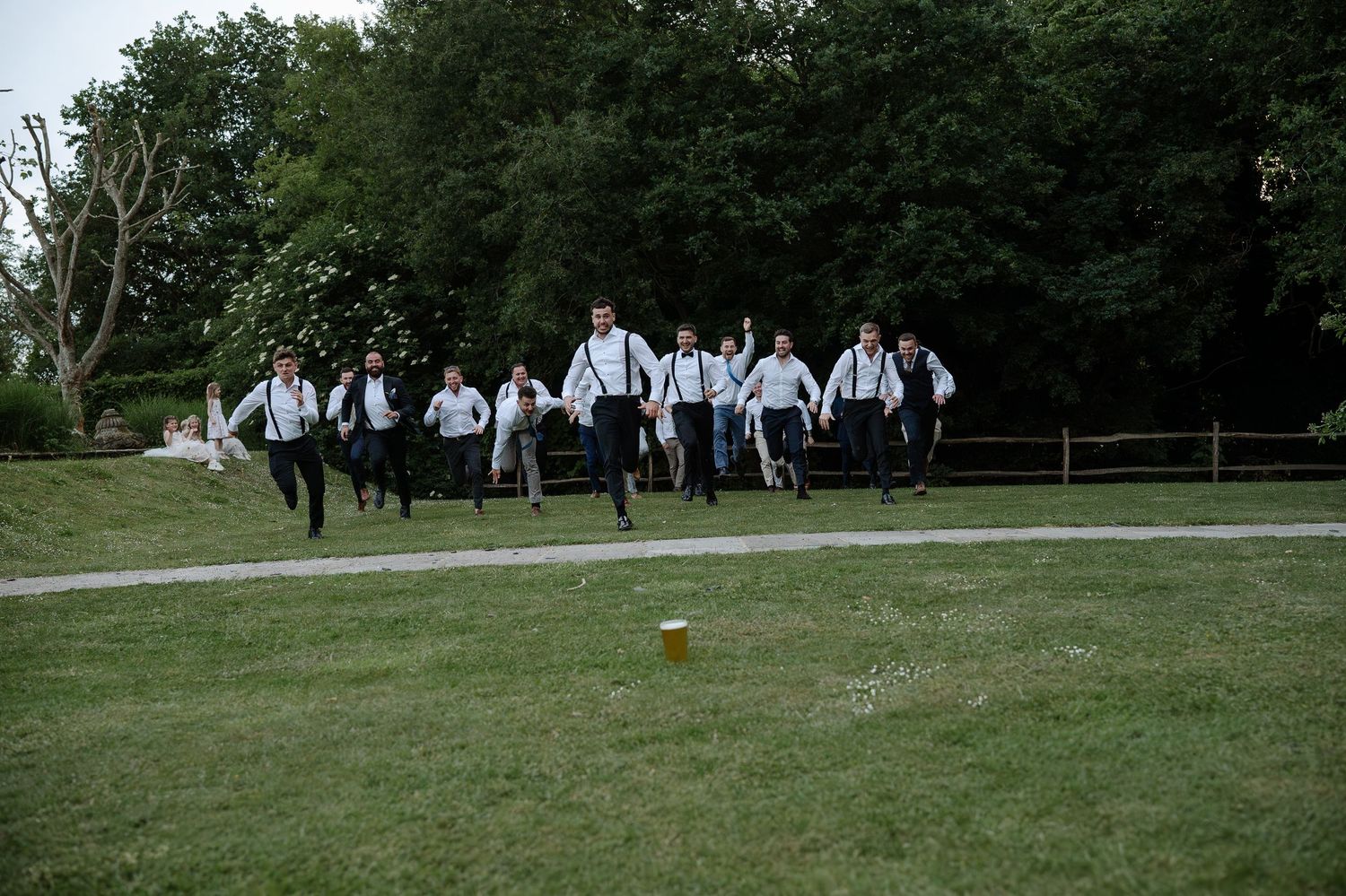 A group of people in formal attire gather on a grassy lawn for a special outdoor event.